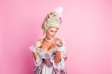 Elegant woman in historical baroque costume posing against pink background, showcasing vintage fashion and aristocratic style