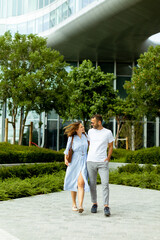 Couple enjoys a joyful stroll through a modern garden in the heart of the city on a sunny afternoon