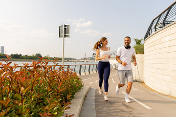 Couple enjoys a joyful run along the scenic waterfront path on a sunny afternoon