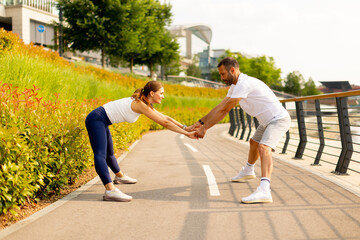 Couple engages in fun outdoor workout on a sunny day beside a vibrant garden pathway