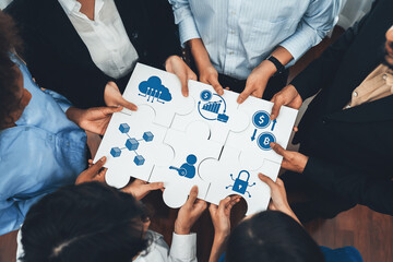 Professionals collaborate over puzzle pieces illustrating various financial and technological concepts in a modern workspace. The engaging activity symbolizes teamwork and innovation. Amity