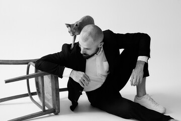 A stylish man poses with his hairless cat, creating a unique and artistic portrait.