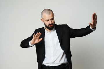 A man in a suit makes a stop gesture in a studio setting, showing denial.