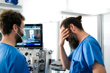 Fototapeta premium Stressed doctor touching face while looking at medical scan results on computer screen
