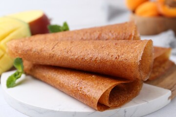Delicious fruit leather rolls, mint and mango on table, closeup
