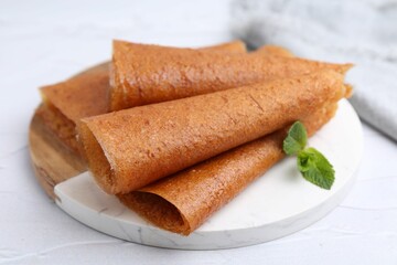 Delicious fruit leather rolls and mint on white table, closeup
