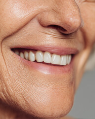 Obraz premium A senior woman with a smile on her face and a white toothbrush in her mouth. Concept of happiness and positivity