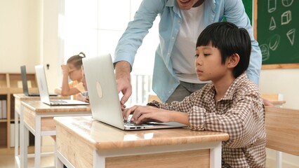 Caucasian teacher helping asian student coding engineering prompt while diverse student using...