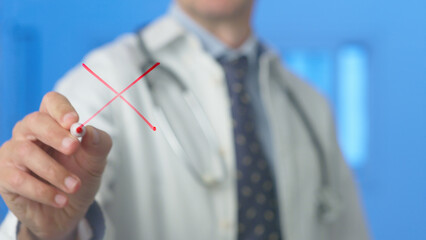 Doctor is drawing a red cross sign on a transparent screen, indicating denial, rejection, or...