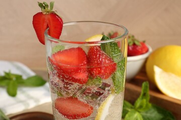 Tasty refreshing drink with strawberries, lemon and mint on table, closeup