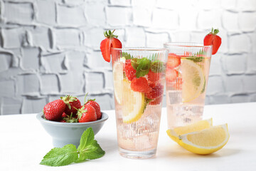 Tasty refreshing drink with strawberries, lemon and mint on white table