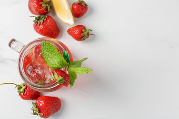 Refreshing drink with strawberries, ice and mint on white table, flat lay. Space for text