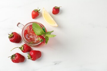 Refreshing drink with strawberries, ice and mint on white table, flat lay. Space for text