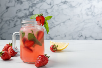 Refreshing drink with strawberries and mint on white table against grey marble background, closeup. Space for text