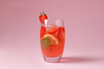 Refreshing drink with strawberries, mint, lemon and ice in glass on pink background, closeup