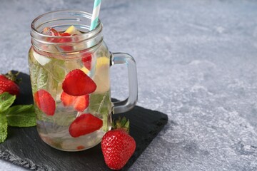 Refreshing drink with strawberries, ice and mint on grey textured table, closeup. Space for text