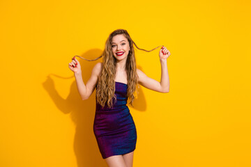 Stylish young female posing in a colorful dress against a vibrant yellow background exuding...