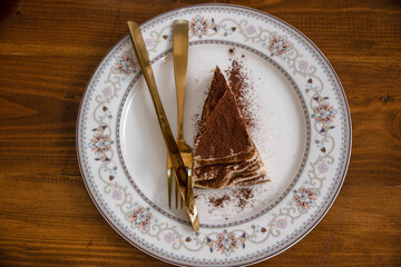 Triangular tiramisu with chocolate chips on a round plate on a table, top view