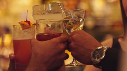 Closeup cropped hand group friends making a toast with cocktail martini, margarita, paloma, old fashioned at luxurious bar, lively conversation drinks celebrating a special party nightclub. Vinosity.