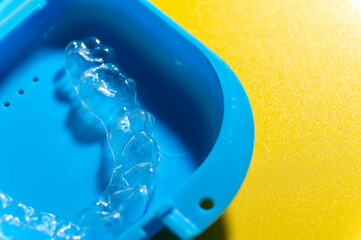 Close-up Blue plastic case with transparent brackets on a peach background. Invisible removable...