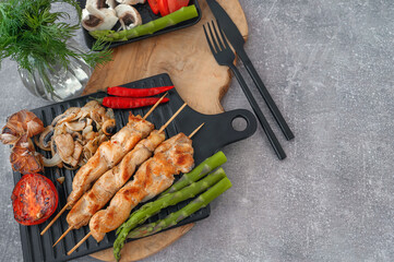 Barbecue on bamboo sticks. Grilled chicken kebab with mushrooms, asparagus and tomato. Red hot kebab. Top view, copy space