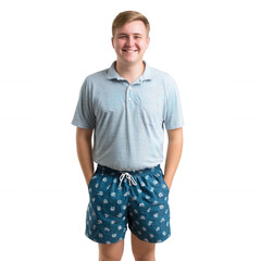 Obraz premium Young man smiling confidently, wearing a casual outfit with a polo shirt and patterned shorts, standing with hands in pockets, isolated on a white background.