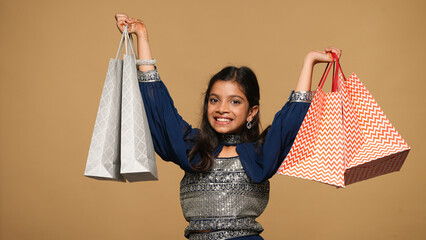 Portraits of kid girl wearing festive outfit and holding gift bags,gift boxes and garlands fro...