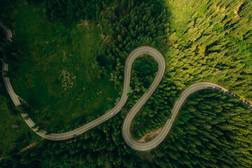 Fototapeta premium Top view or aerial of the road passing through the mountain and green forest.Curve asphalt road on mountain forest summer.