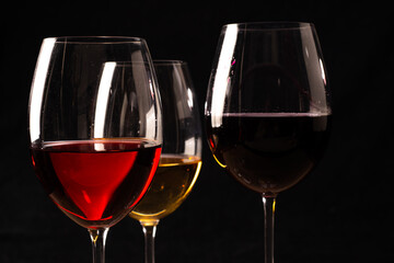 Crystal glasses with red and white wine
over rustic wooden table on black background