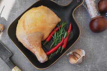 Raw chicken leg. A piece of fresh raw chicken leg with red chilli. displayed on a black stylish ceramic baking pan. Top view