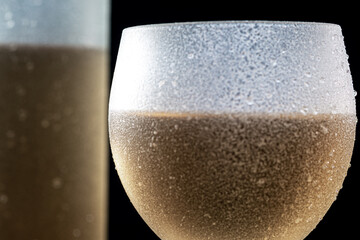 
Close-up of a crystal glass with white wine and bottle of wine served well chilled,
on black...