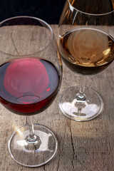 Crystal glasses with red and white wine
over rustic wooden table on black background