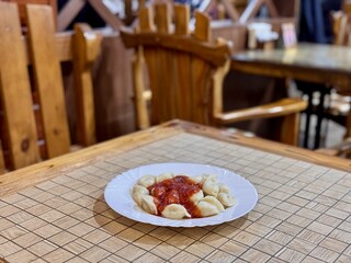 A plate of Delicious Dumplings served with a rich, flavorful Tomato Sauce that enhances taste. Enjoy a plate of freshly boiled dumplings topped with savory tomato sauce for a hearty meal any time