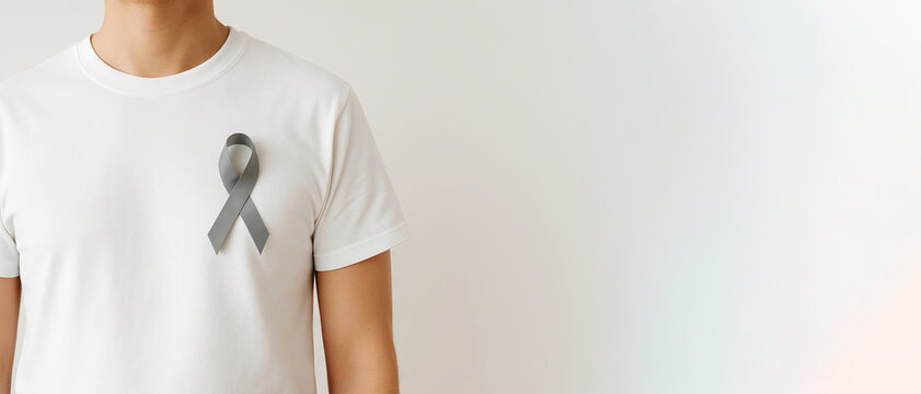 Unrecognizable man wearing gray awareness ribbon on plain white shirt. concept of health support, awareness campaigns, brain cancer, type 2 diabetesWide banner, copy space, white background