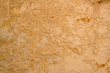 Background texture of wall with coarse stucco or concrete in warm yellow colour