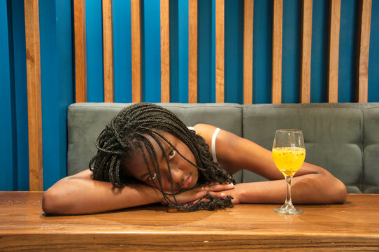 Sad young woman resting head on table in restaurant with cocktail