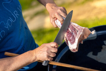 Fresh pork knuckle in hand while cutting and cooking. Cooking and baking goulash at home and in nature. Boning meat. Food preparation, Ingredients