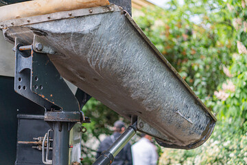 Rusty, curved concrete mixer truck part, partially obscured in wooded environment