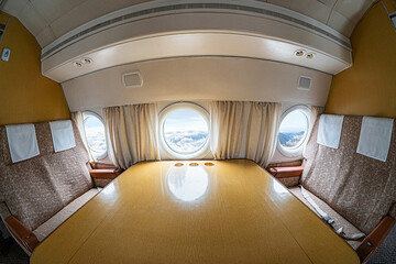 Luxurious airplane cockpit with large windows, wooden paneling, plush curtains, small light...