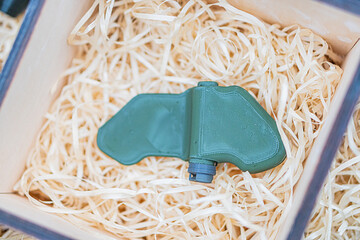 A green, rounded explosive mine sits on a bed of straw or shredded paper The object is centered and...