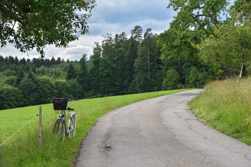the bicycle is standing on the side of the road on a hill near a clearing


