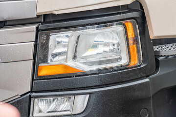 Close-up view of a black trucks front right side, focusing on the headlight assembly and minor alignment issue with hood The headlight is predominantly white, containing multiple bulbs and an unlit
