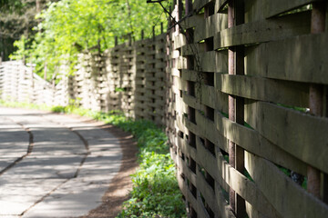 Road in a village with trees and beautiful wodden fence at the right side. Sunny summer day.