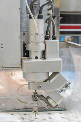 Image shows an industrial robot, a cylindrical metal structure with multiple connections and hoses in a metallic industrial setting Muted color palette with grays, whites, and darker areas No peopl