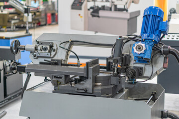 Close-up of a large industrial machine, made of heavy steel or metal, with moving parts and gears visible Artificial lighting, casting shadows Blurred background suggests additional machinery Take