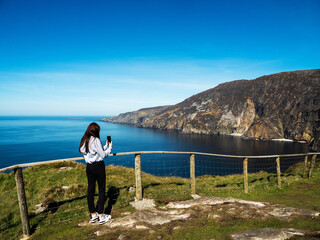 Teenager girl sightseeing stunning Slieve League cliff nature scenery and Atlantic ocean. Blue...