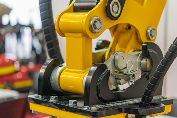 Fototapeta premium Yellow and black industrial robot arm in an assembly setting, with articulated joints, artificial lighting, and a blurred background suggesting other machinery