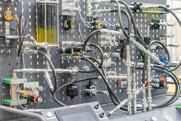 Industrial machinery metal structure with tubes and hoses, dominated by metallic greys, artificial lighting