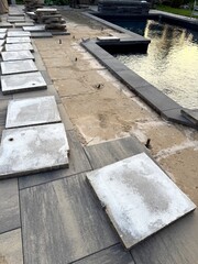 Luxury backyard remodel with excavation and leveling uneven pavers that sunk and shifted with joint sand. Stunning grey pavers lifted, removed, measured, and releveled using rubber mallet around pool.