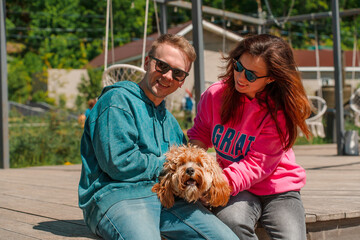 A young woman and man, couple, with brown curly-haired Labradoodle dog, animals are best friends